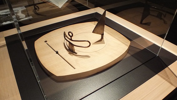 Dies ist eines der Spielfelder Giacomettis - mit dem Titel "Familie" (1931/1932). Zu sehen sind eine Frau, ein Segel und ein Kind. Die Rillen auf dem Brett regen den Betrachter dazu an, sich immer neue Positionen der drei Figuren im Geiste auszumalen. (Quelle: ndr.de)